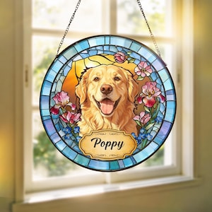 May include: Circular stained glass window art depicting a smiling golden retriever dog, with the name "Poppy" on a banner. The design incorporates blue, pink, and yellow hues, floral details, and a hanging chain.