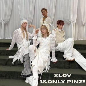 May include: A group of four people dressed in white and cream-colored outfits, posing on green steps in front of white curtains. The outfits include lace, sheer fabrics, and accessories. The text "XLOV 1&ONLY PINZ!!" is visible.