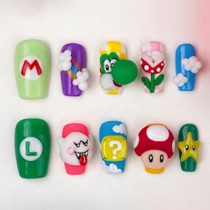 May include: A set of ten colorful, decorated acrylic nails featuring various characters and symbols from the Super Mario video game franchise. Designs include Mario, Luigi, Yoshi, a mushroom, and other iconic elements.