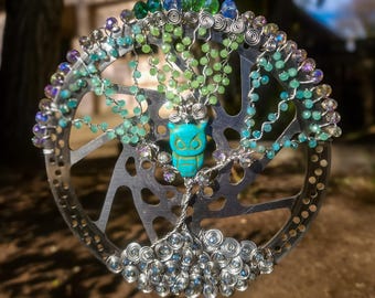 Un colorido búho en un árbol atrapasoles hecho con un engranaje de bicicleta reutilizado