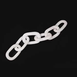 Puede incluir: Una cadena blanca con eslabones ovalados sobre un fondo negro. La cadena est&aacute; hecha de un material s&oacute;lido y opaco, dispuesta en diagonal. Los eslabones son de tama&ntilde;o y forma uniformes.