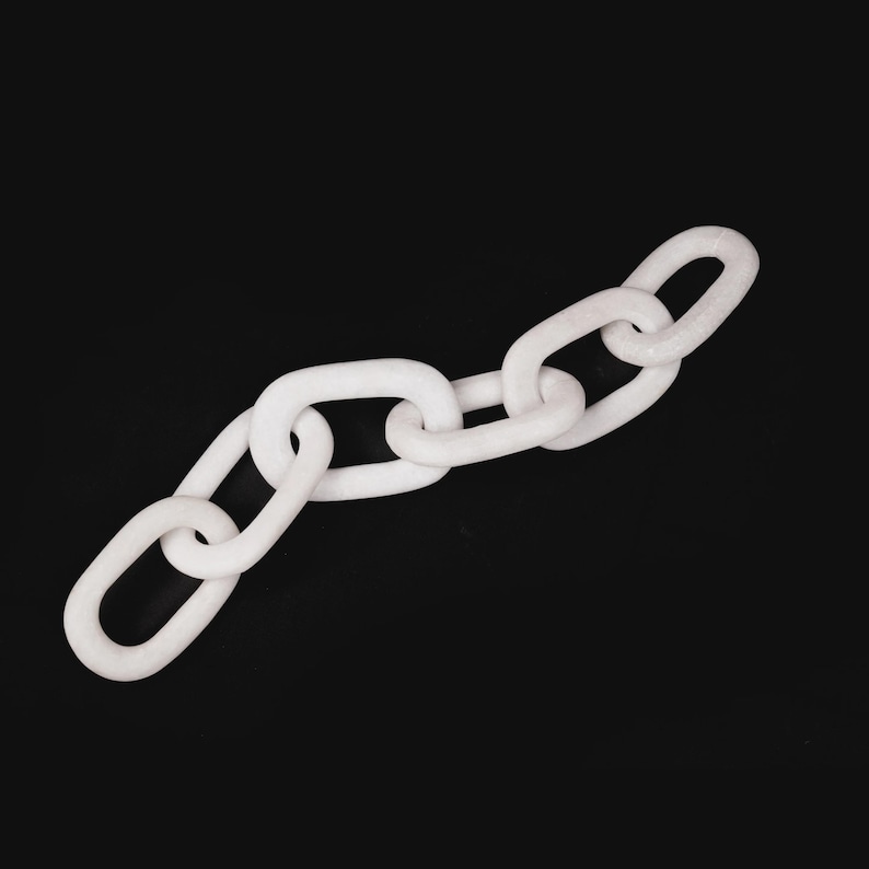 Puede incluir: Una cadena blanca con eslabones ovalados sobre un fondo negro. La cadena est&aacute; hecha de un material s&oacute;lido y opaco, dispuesta en diagonal. Los eslabones son de tama&ntilde;o y forma uniformes.