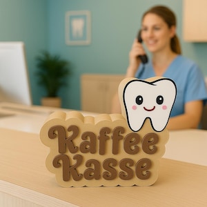 Pode incluir: Uma placa decorativa para um consultório dentário, com um dente de desenho animado e as palavras "Kaffee Kasse" em letras marrons. A placa é bege e está sobre uma superfície clara.