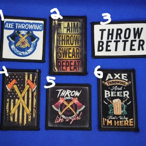 May include: A collection of six rectangular patches with various axe-throwing-themed designs. The patches feature text like "Axe Throwing," "Throw Better," and "Throw like a girl." The color palette includes black, white, red, and gold.