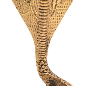 Pode incluir: Uma estátua de cobra dourada e detalhada. A cobra é retratada com o capelo aberto e seu corpo é intrincadamente texturizado. A base é enrolada e o design geral é ornamentado. A estátua é provavelmente feita de metal.