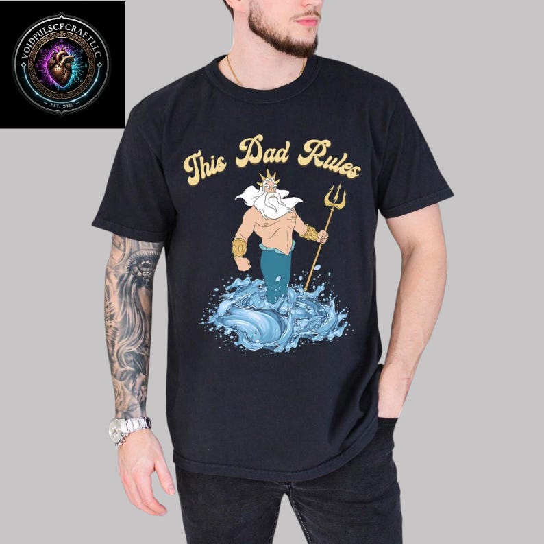 May include: Black t-shirt with a cartoon illustration of a sea god holding a trident, emerging from water. The text "This Dad Rules" is in gold script above the illustration. The VoidpulsecraftLLC logo is in the upper left corner.