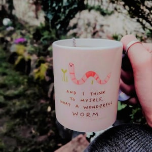 Könnte beinhalten: Eine rosa Keramiktasse mit einer Cartoon-Wurm-Illustration und dem Text "And I think to myself, what a wonderful worm."
