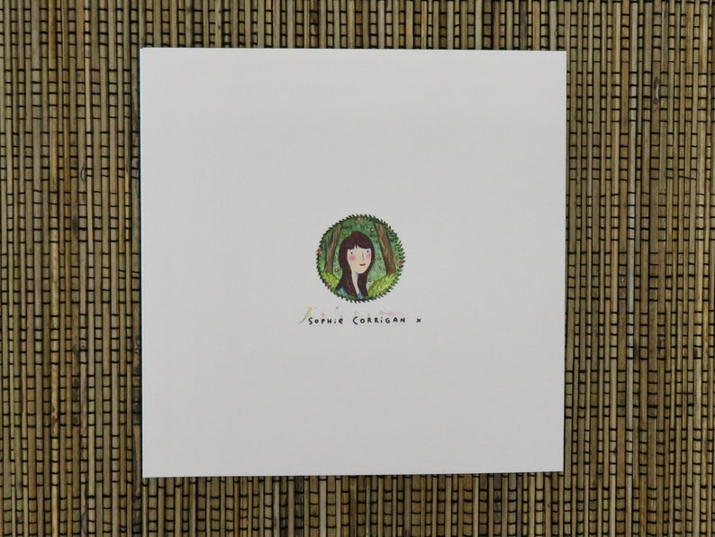 May include: A white card with a green circle containing a drawing of a woman with brown hair and a green dress. The text "Sophie Corrigan x" is written below the circle.