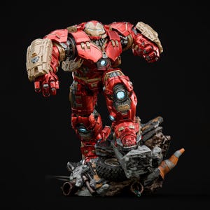 May include: A large, metallic red and gold armored robot figure standing in a dynamic pose. The figure features glowing blue circular accents on the chest and legs, with bulky shoulder and arm plating. It stands atop a base of gray rubble.