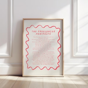 May include: A framed print featuring the text "THE FREELANCER MANIFESTO" in black and red, with a wavy red border. The print is displayed against a white wall, creating a minimalist aesthetic.