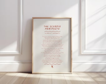 May include: A framed print with the text "THE SCORPIO MANIFESTO" in red. The print includes a list of affirmations and the dates October 23 - November 21. The frame is a light brown color, and the background is white.