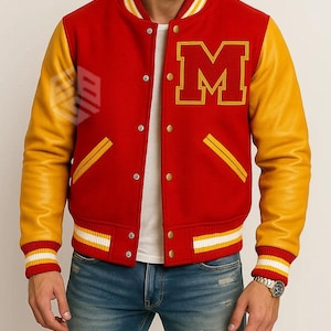Op de afbeelding: Rode en gele varsity jas met de letter "M" op de borst. De jas heeft gele leren mouwen, een rode body en gestreepte manchetten en zoom. Het heeft een knoopsluiting en twee voorzakken.