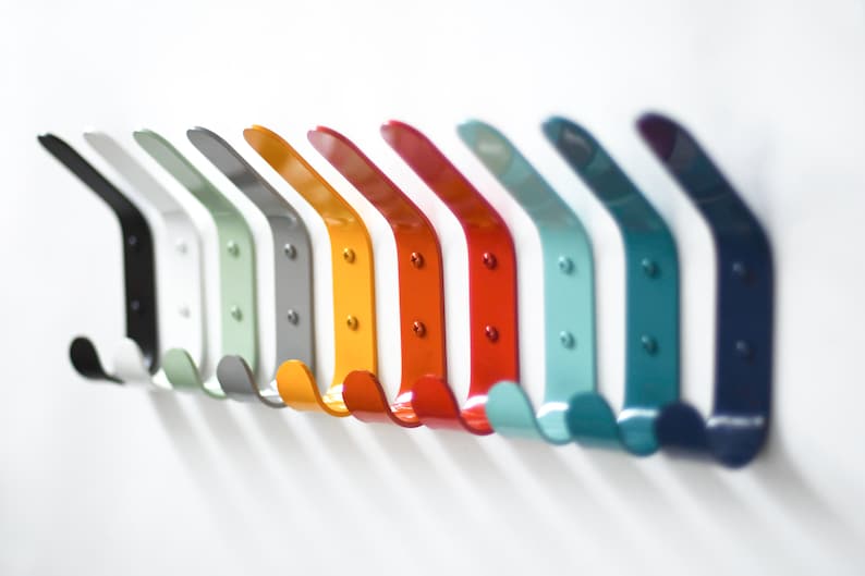 May include: A row of ten metal hooks in various colors, including black, white, green, gray, yellow, red, orange, light blue, dark blue, and navy blue. The hooks are all the same shape and size, and they are arranged in a line on a white background.