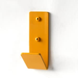 May include: A yellow metal hook mounted on a white wall. The hook has two screws visible.