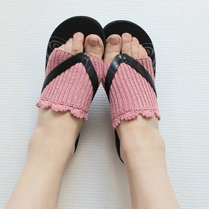 May include: A pair of pink knitted toe socks with a crocheted trim worn with black flip flops.