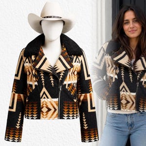 May include: A cropped jacket featuring a black, tan, and cream geometric pattern with a black faux-shearling collar and an asymmetrical front zipper closure. The jacket is displayed on a mannequin wearing a white cowboy hat with a decorative band.