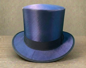 May include: A top hat with a deep blue, iridescent satin finish that shifts in tone. The hat features a structured cylindrical crown and a wide, curved brim, accented by a solid black grosgrain ribbon band encircling the base of the crown.