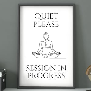 Könnte beinhalten: Gerahmter Druck mit dem Text "QUIET PLEASE SESSION IN PROGRESS". Das Kunstwerk zeigt eine minimalistische Strichzeichnung einer Person in einer sitzenden Yoga-Pose. Der Rahmen ist dunkelgrau und der Hintergrund ist weiß.