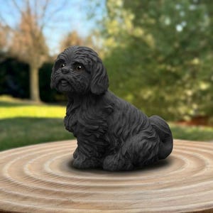 May include: A black Shih Tzu dog statue with detailed fur texture, sitting on a wooden surface. The dog has brown eyes and a friendly expression. The statue is a decorative item for dog lovers.