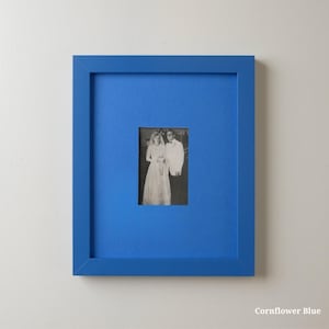 Op de afbeelding: Een ingelijste zwart-witfoto van een bruidspaar. De lijst is helder korenbloemblauw, met een bijpassende passe-partout. De foto is gecentreerd in de lijst, wat een opvallend visueel contrast cre&euml;ert. De tekst "Cornflower Blue" staat rechtsonder.
