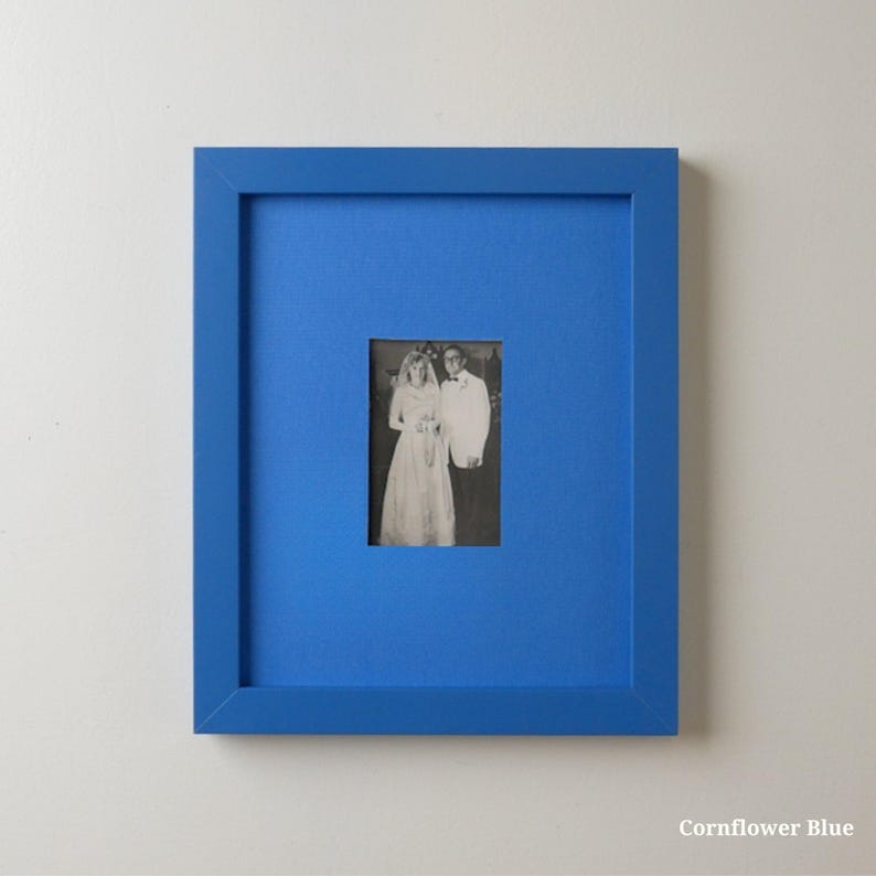 Op de afbeelding: Een ingelijste zwart-witfoto van een bruidspaar. De lijst is helder korenbloemblauw, met een bijpassende passe-partout. De foto is gecentreerd in de lijst, wat een opvallend visueel contrast cre&euml;ert. De tekst "Cornflower Blue" staat rechtsonder.