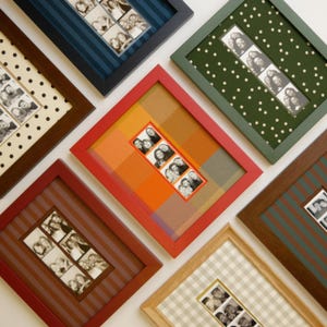 May include: A collection of seven rectangular picture frames featuring various colored mats with patterns including stripes, polka dots, and plaid. Each frame contains a vertical strip of black and white photo booth portraits showing multiple people.