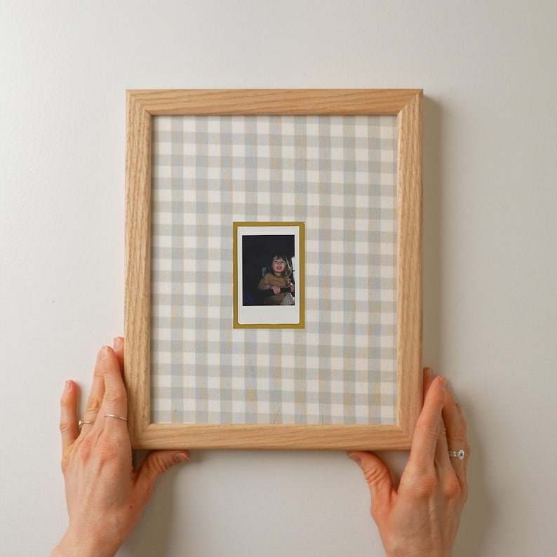patterned Fabric covered mat for polaroid instax mini, made for 8x10 frame, gingham and natural wood, hands holding frame to show scale