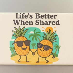 以下が含まれることがあります： 「Life's Better When Shared」の文字と、ビーチで手をつないでいる2つの擬人化されたパイナップルの漫画イラストが描かれた長方形のサイン。パイナップルはサングラスをかけています。