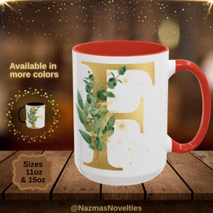 Può includere: Tazza in ceramica bianca con interno e manico rossi, con un design dorato della lettera "F" e accenti botanici verdi. Disponibile nelle misure da 312 ml e 425 ml. Il testo "Disponibile in più colori" è visualizzato.