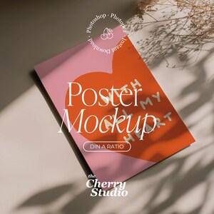 Puede incluir: Una maqueta de póster con un diseño de corazón rosa y naranja. Las palabras "Poster Mockup" están en escritura blanca, con el texto "DIN A RATIO" debajo. El logotipo de Cherry Studio está en la parte inferior, con las palabras "Photoshop" e "Instant Download" en un círculo.