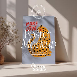 Puede incluir: Maqueta de póster con una ilustración de leopardo con manchas negras sobre un fondo azul claro. Las palabras "MORE LOVE" están en rojo y "Poster Mockup" en blanco. El logotipo de The Cherry Studio está en la parte inferior.