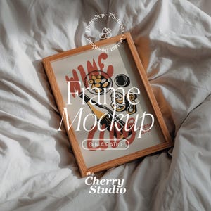 Puede incluir: Una maqueta de marco de madera con una impresión que presenta una ilustración con temática de vino en rojo, amarillo y negro. El texto "Frame Mockup" se muestra de forma destacada, junto con "DIN A RATIO" y "the Cherry Studio". El marco descansa sobre una superficie blanca texturizada.
