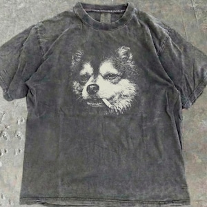 Pode incluir: Camiseta cinza escuro com uma estampa de um cachorro fumando um cigarro. O rosto do cachorro é branco sobre o tecido escuro. A camiseta tem gola redonda e mangas curtas, com um visual vintage desbotado.
