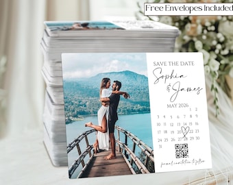 May include: A stack of save-the-date cards featuring a couple embracing on a wooden bridge with a scenic backdrop. The cards include the text "Save the Date," names "Sophia & James," and the date "May 2026." A calendar and QR code are also present.