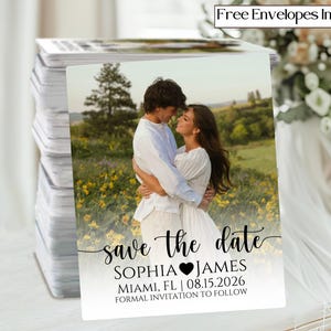 May include: A stack of save-the-date cards featuring a couple embracing in a field of yellow flowers. The cards have the text "save the date" with the names Sophia and James, Miami, FL, and the date 08.15.2026. The cards include free envelopes.