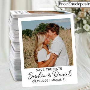 May include: A stack of white Save the Date cards with a photo of a couple. The cards have the text "SAVE THE DATE" and the names "Sophia & Daniel" with the date "08.15.2026 | MIAMI, FL". The words "Free Envelopes Included" are at the top.