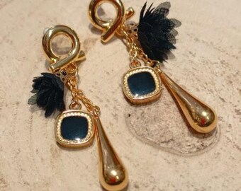 May include: A pair of gold earrings with black fabric flowers and dark blue glass stones. The earrings have a teardrop shape and are dangling.