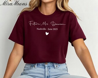 May include: Burgundy t-shirt with the text "Future Mrs. Dawson" in a script font, along with "Nashville - June 2025" and a small heart. The shirt is a solid color and appears to be made of soft material.