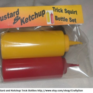 May include: A clear plastic bag containing two squeeze bottles, one yellow and one red. The bottles are labeled "Mustard & Ketchup Trick Squirt Bottle Set".
