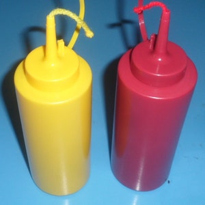 May include: Two plastic condiment bottles with squeeze tops and twist-on lids. The bottle on the left is yellow and the bottle on the right is red.