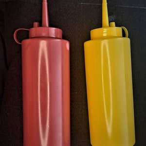 May include: Two plastic condiment bottles, one red and one yellow, with squeeze tops and narrow spouts.