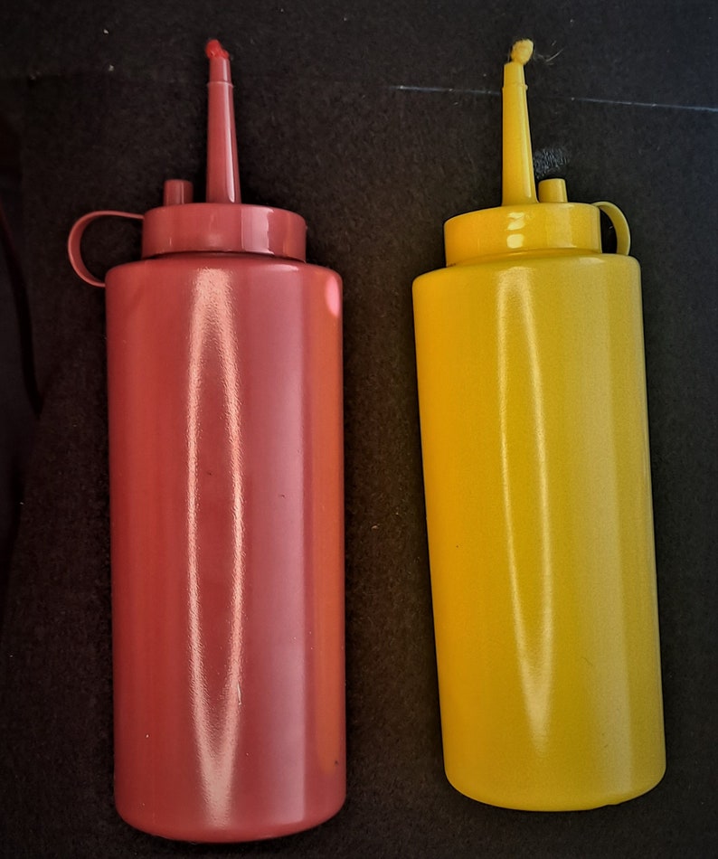 May include: Two plastic condiment bottles, one red and one yellow, with squeeze tops and narrow spouts.