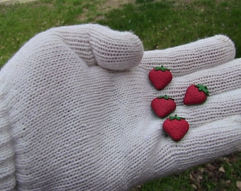 May include: A white knitted glove with five red plastic strawberry buttons attached to it.