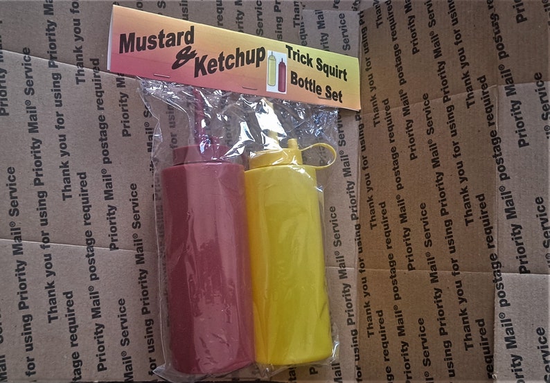 May include: Two plastic squeeze bottles, one red and one yellow, labeled "Mustard & Ketchup Trick Squirt Bottle Set".