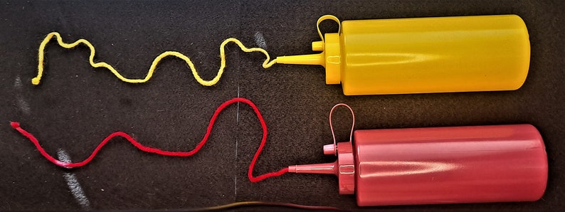 May include: Two condiment bottles, one yellow and one red, with a squiggle of yellow sauce coming out of the yellow bottle and a squiggle of red sauce coming out of the red bottle.