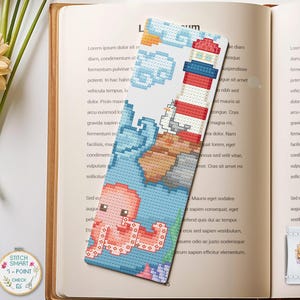 Könnte beinhalten: Handgefertigter Kreuzstich-Lesezeichen mit Leuchtturm, Oktopus und Meereslandschaft. Das Lesezeichen ist rechteckig mit einem blau, rot und weiß Farbschema. Der Text "STITCH SMART" und "1-POINT CHECK" ist auf einem kleinen runden Patch zu sehen.