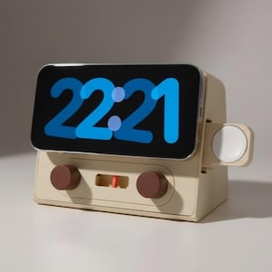 Peut inclure: Station de charge beige pour téléphone et montre, de style rétro. L'écran du téléphone affiche l'heure 22:21 en bleu. La station a deux boutons marron et un socle de chargement de montre blanc.