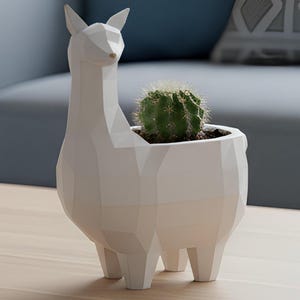 May include: A white geometric llama planter containing a green cactus. The planter has a modern, angular design and is made of a solid white material. The cactus is planted in dark soil.