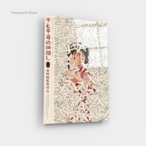 May include: Tempered glass art featuring a scene from the animated film "Spirited Away." The artwork depicts a young girl surrounded by white figures, with Japanese text on the side. The glass has a glossy finish.