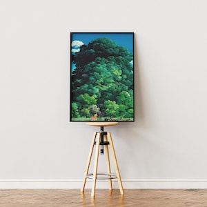 May include: A framed art print depicting a dense green forest under a blue sky. The artwork is presented on a wooden and metal adjustable stool. The print's colours include shades of green, blue, and brown.